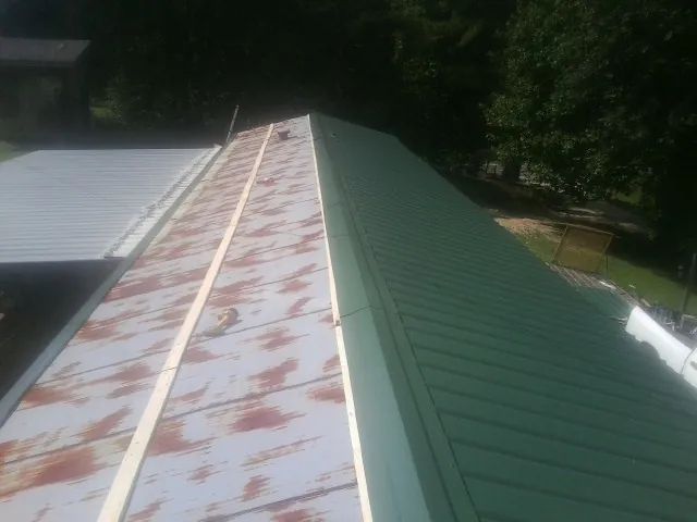 Old rusted panels beside newly installed green metal roofing — Wind Damage Roof Repair by Roofing Brothers in Trenton