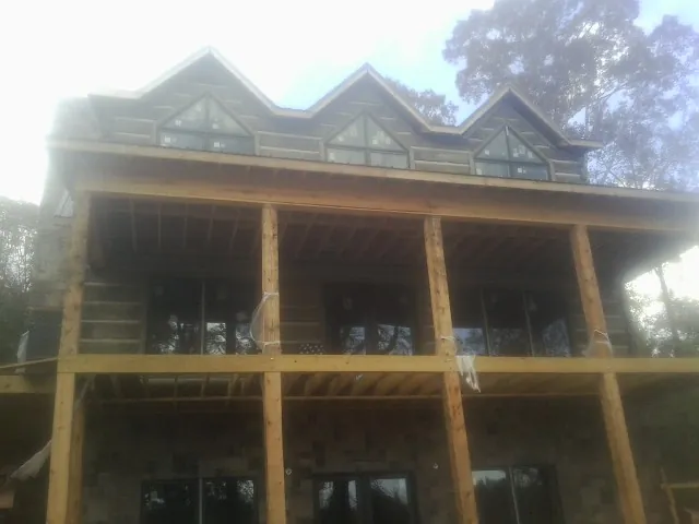 Dormers and porch framing on a large log home under construction — Roof Coating work by our crew in Trenton