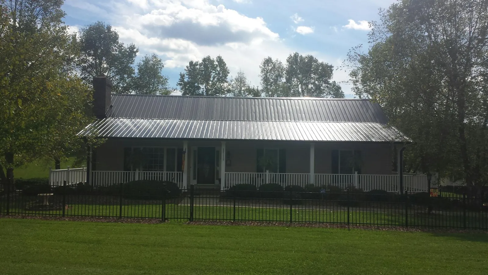 Gray metal roof on a brick ranch with a full width front porch — Gutter Guard Installation work by our crew in Trenton