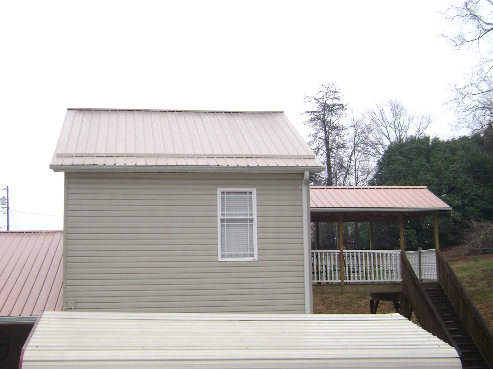 Tan metal roofs on a two story addition and attached porch, from a Roof Replacement job in Trenton